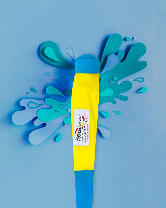 A yellow and blue Foxtail Splash! sits on a blue background with paper cutout water splashes, ready for fun water play with its splash-ready ball.
